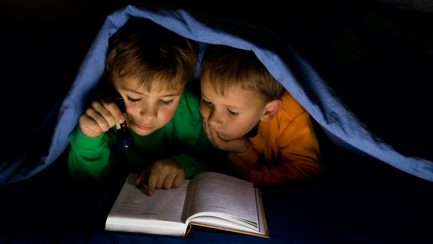 Kids reading under blanket during power outage