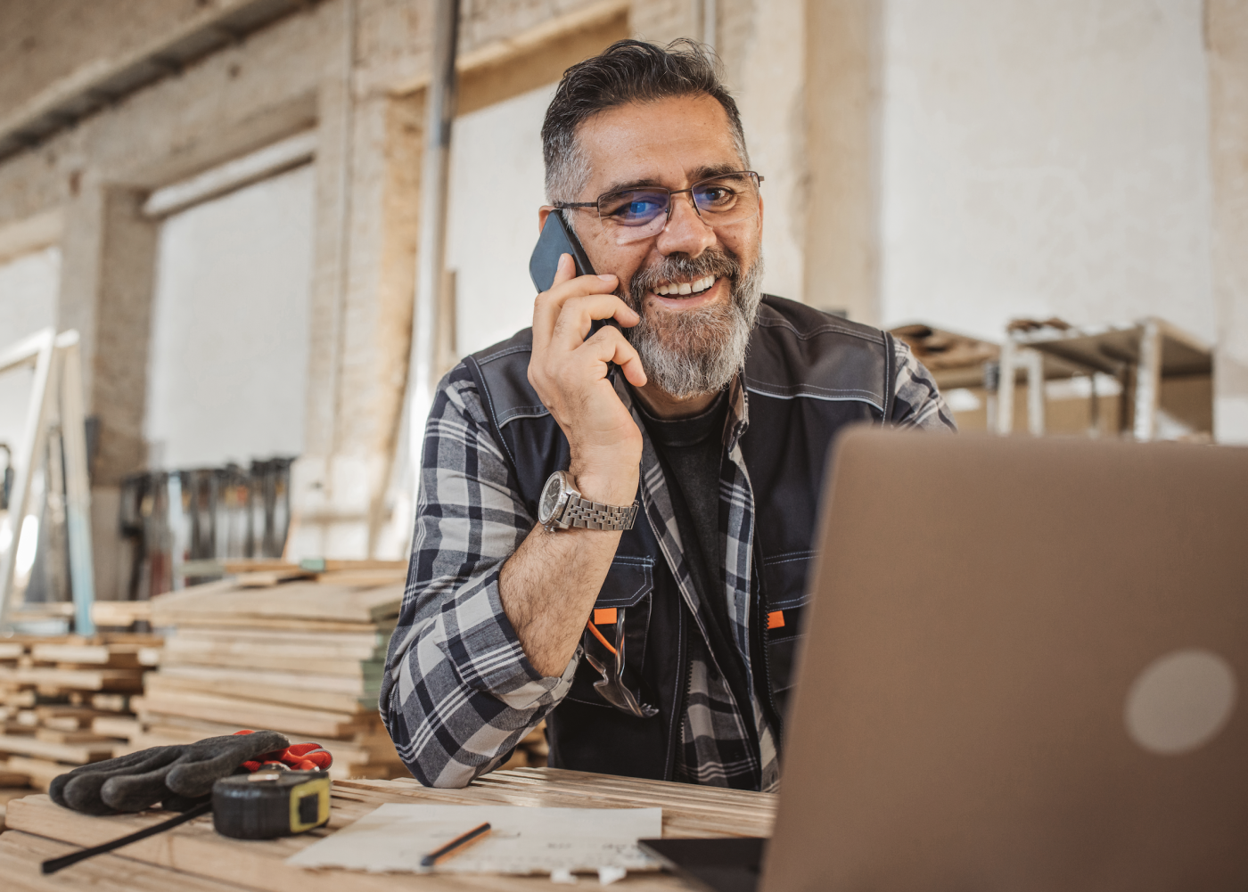 Construction labor male worker using phone and computer to call a client