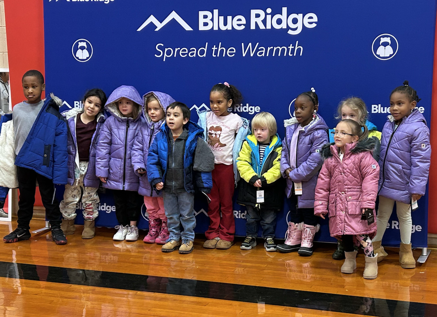 Children with new coats standing in front of STW banner